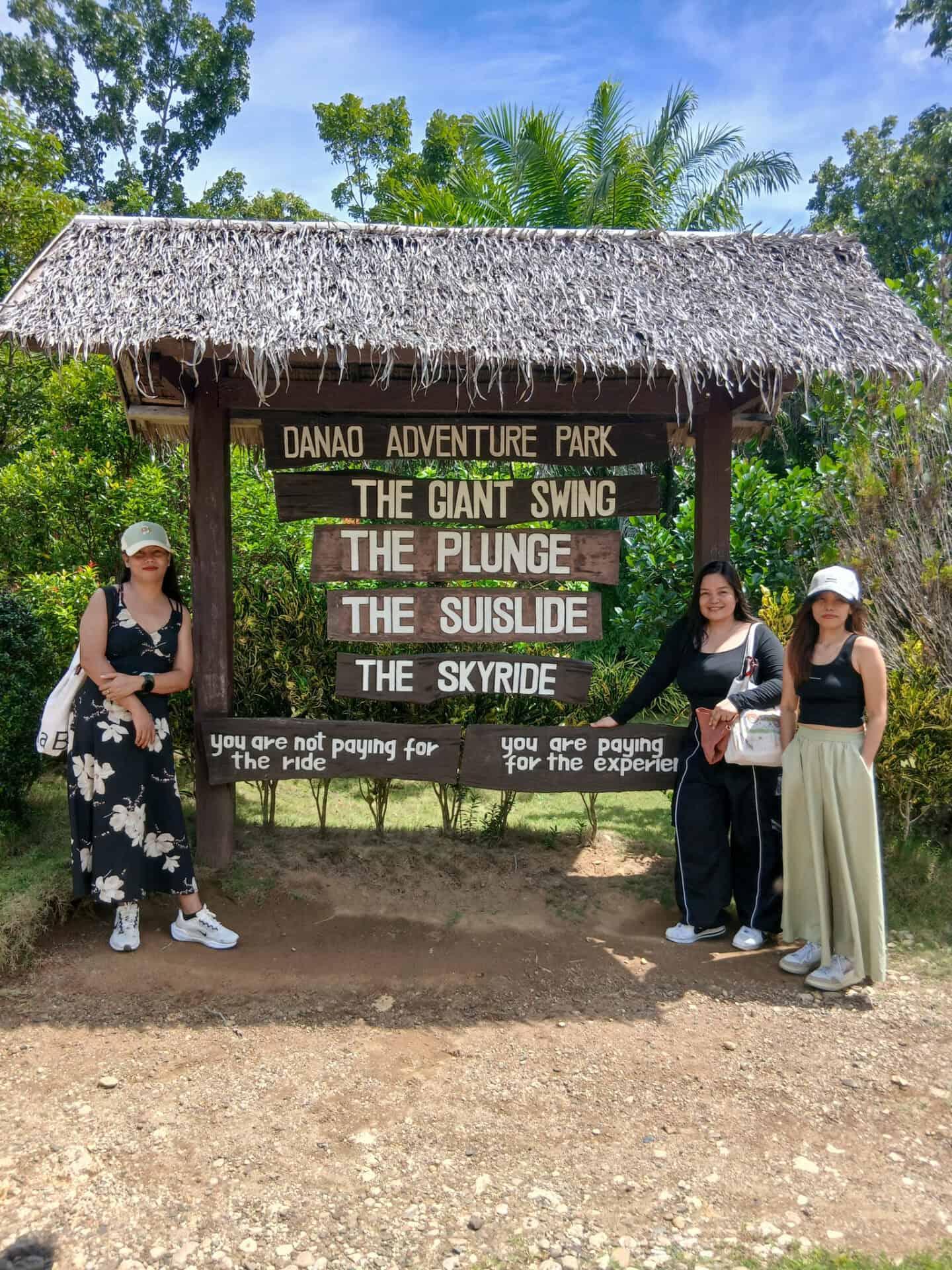 Visitors posing at the entrance sign of Danao Adventure Park in Bohol Island Geopark, home to thrilling outdoor adventure activities.