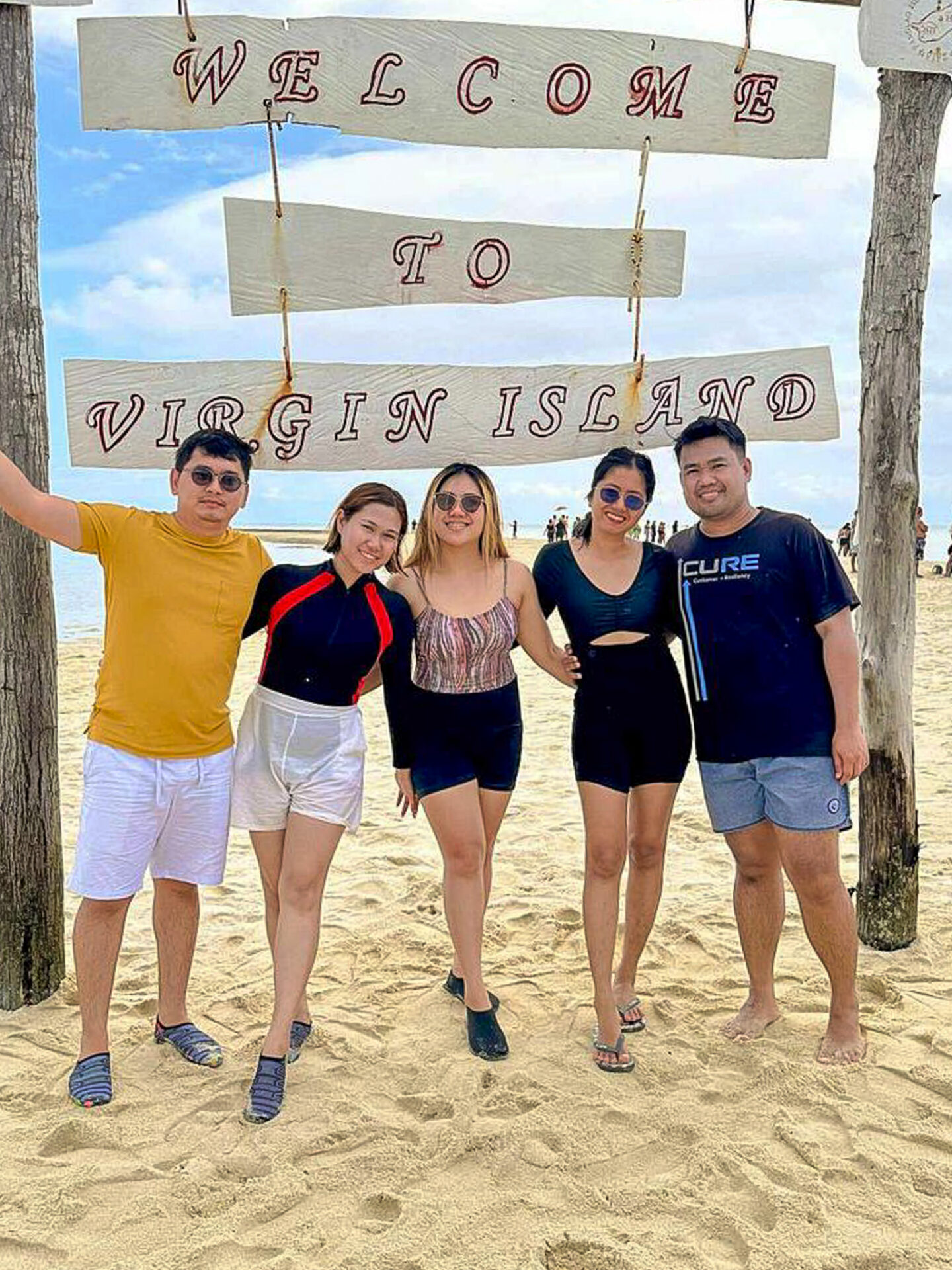 Travelers posing beneath the Welcome to Virgin Island sign on the white sandbar in Bohol Island Geopark, Philippines.
