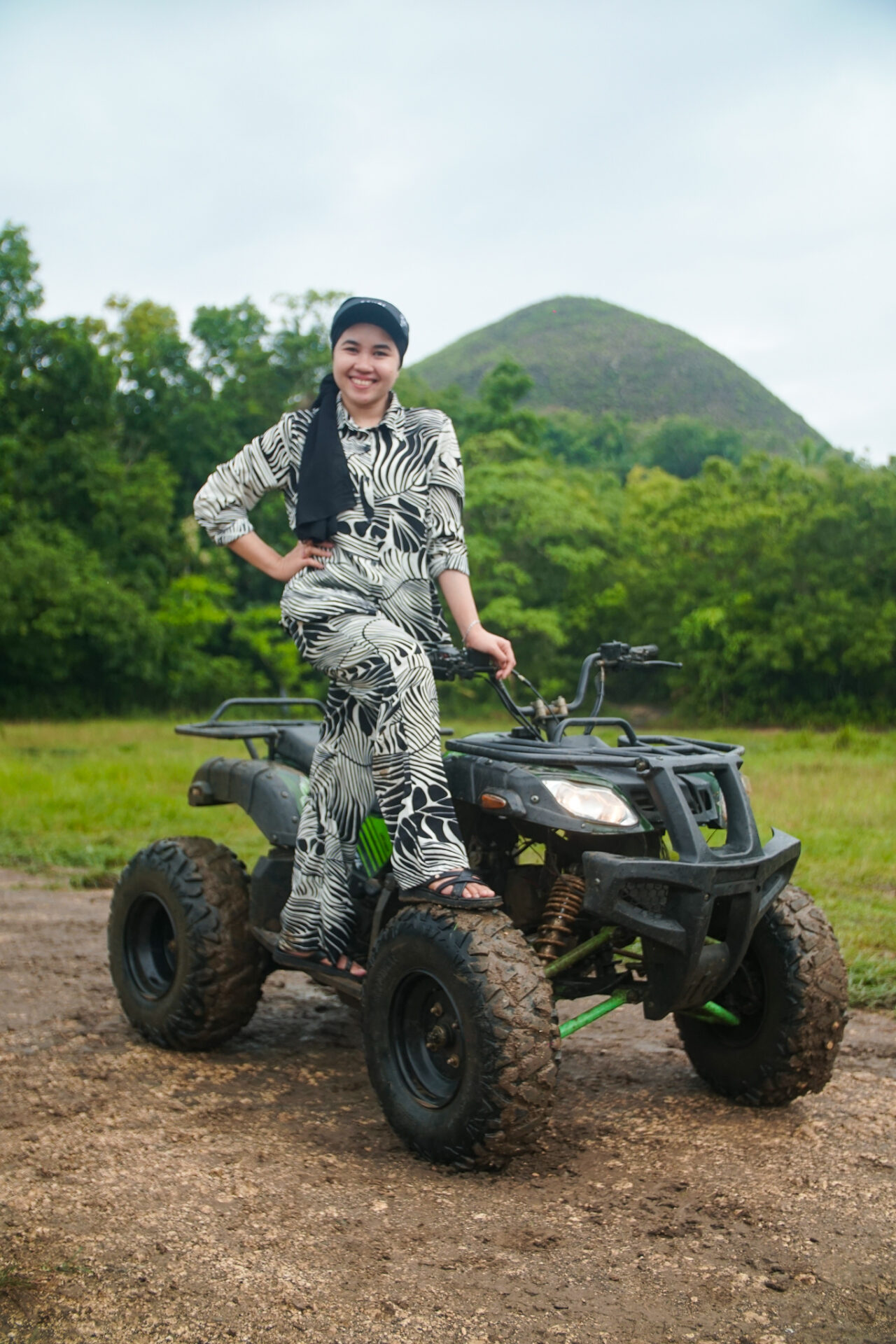 Traveler posing on an ATV with the iconic Chocolate Hills in the background during an off-road adventure in Bohol.