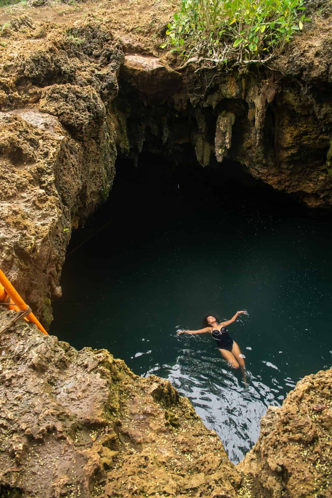 Traveler floating in the crystal-clear waters of Cabagnow Cave Pool surrounded by limestone formations in Anda, Bohol.