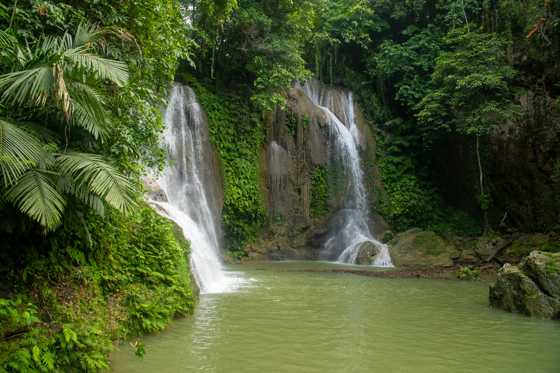 Twin cascading waterfalls surrounded by lush tropical forest at Pahangog Twin Falls in Dimiao, Bohol Island Geopark.