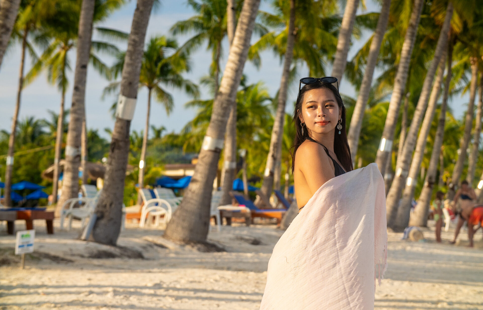 Visitor enjoying the white sand beach and coconut-lined shoreline in Panglao, Bohol during golden hour.